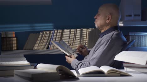 Old-man-reading-a-book-in-the-dark-room.